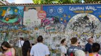 John Lennon Wall (Lennonova Zeď) Di Praha Adalah Dinding Graffiti Ikonik Yang Penuh Warna, Terletak Di Velkopřevorské Náměstí (Dekat Kampa Island, Malá Strana), Tidak Jauh Dari Charles Bridge. Dinding Ini Milik Knights Of Malta.
